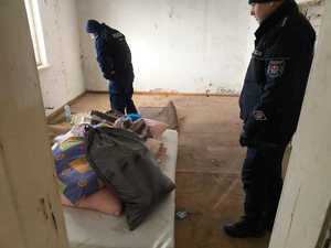 policjanci kontrolujący pustostany, przy radiowozie z kocami, w budynku