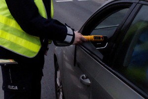 policjant trzyma urządzenie do badania trzeźwości